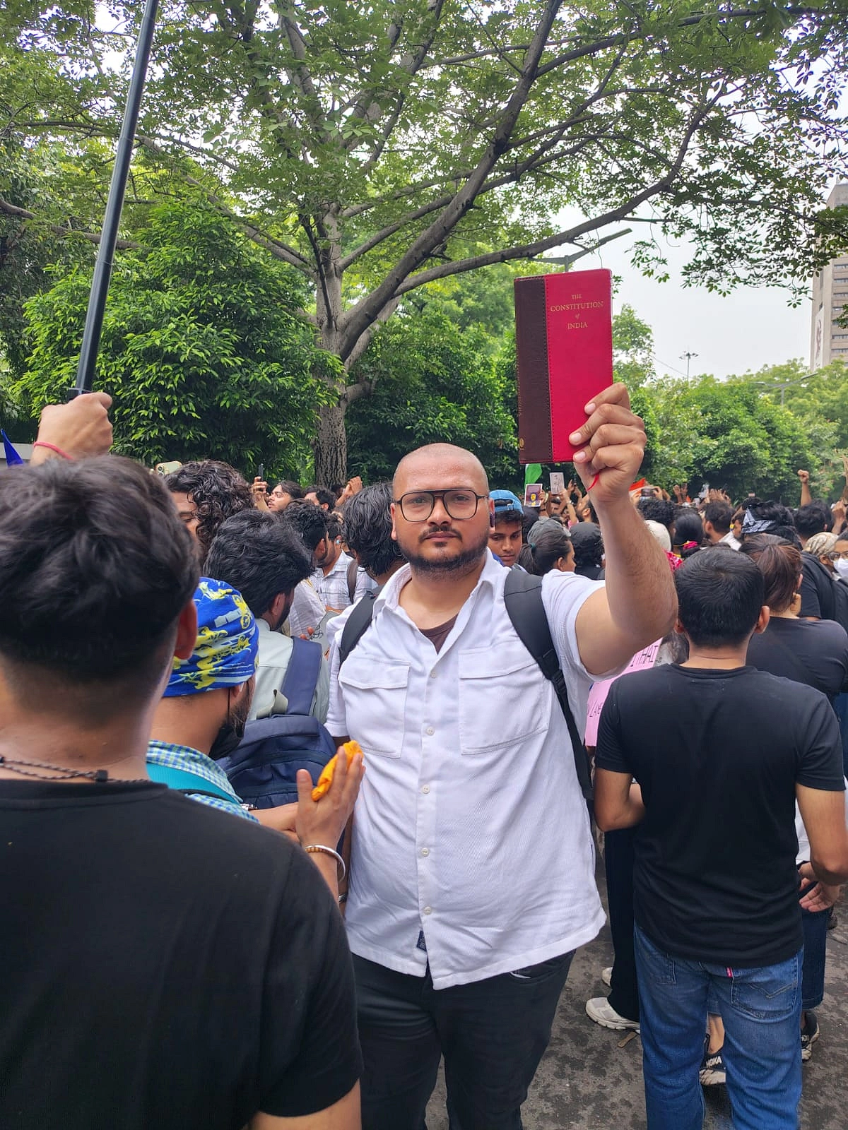 The author holds a copy of the Indian Constitution during the Cockroach Movement at Jantar Mantar in New Delhi.